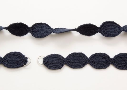 Close up plan view of a navy blue cotton woven ovals necklace with open Sterling Silver endings on a white background. 