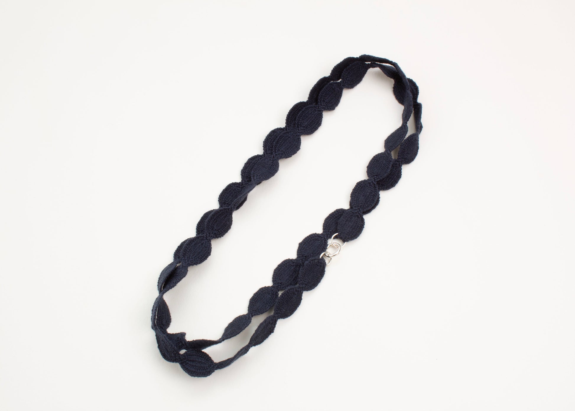 Plan view of a navy blue cotton woven ovals necklace with Sterling Silver endings closed and wrapped in two loops on a white background. 