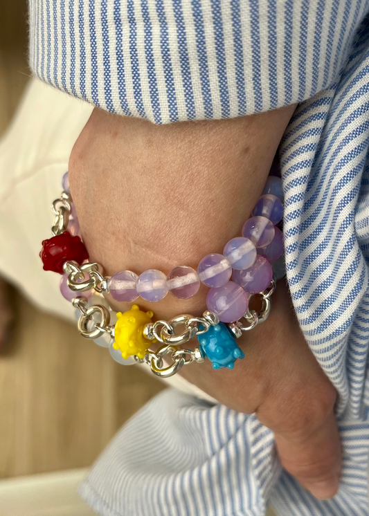 Overhead view of Opalite bracelet stack with one urchin lampwork glass charm each in 3 different colours.