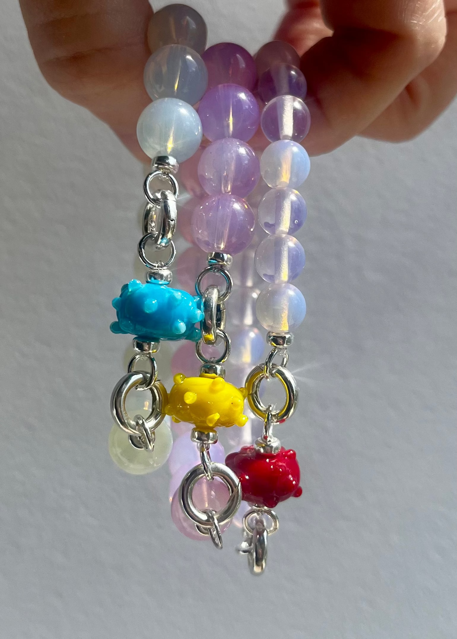 Front view of Opalite bracelet stack with one urchin lampwork glass charm each in 3 different colours on a white background.