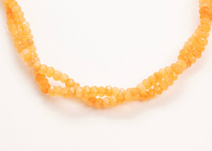 Close up of drop detail of an orange_small_quartzite_beads_strand_on a white background