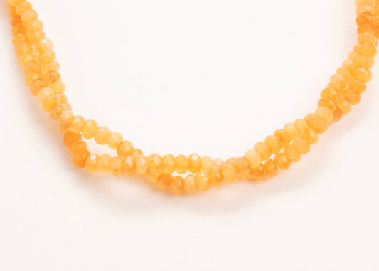 Close up of drop detail of an orange_small_quartzite_beads_strand_on a white background