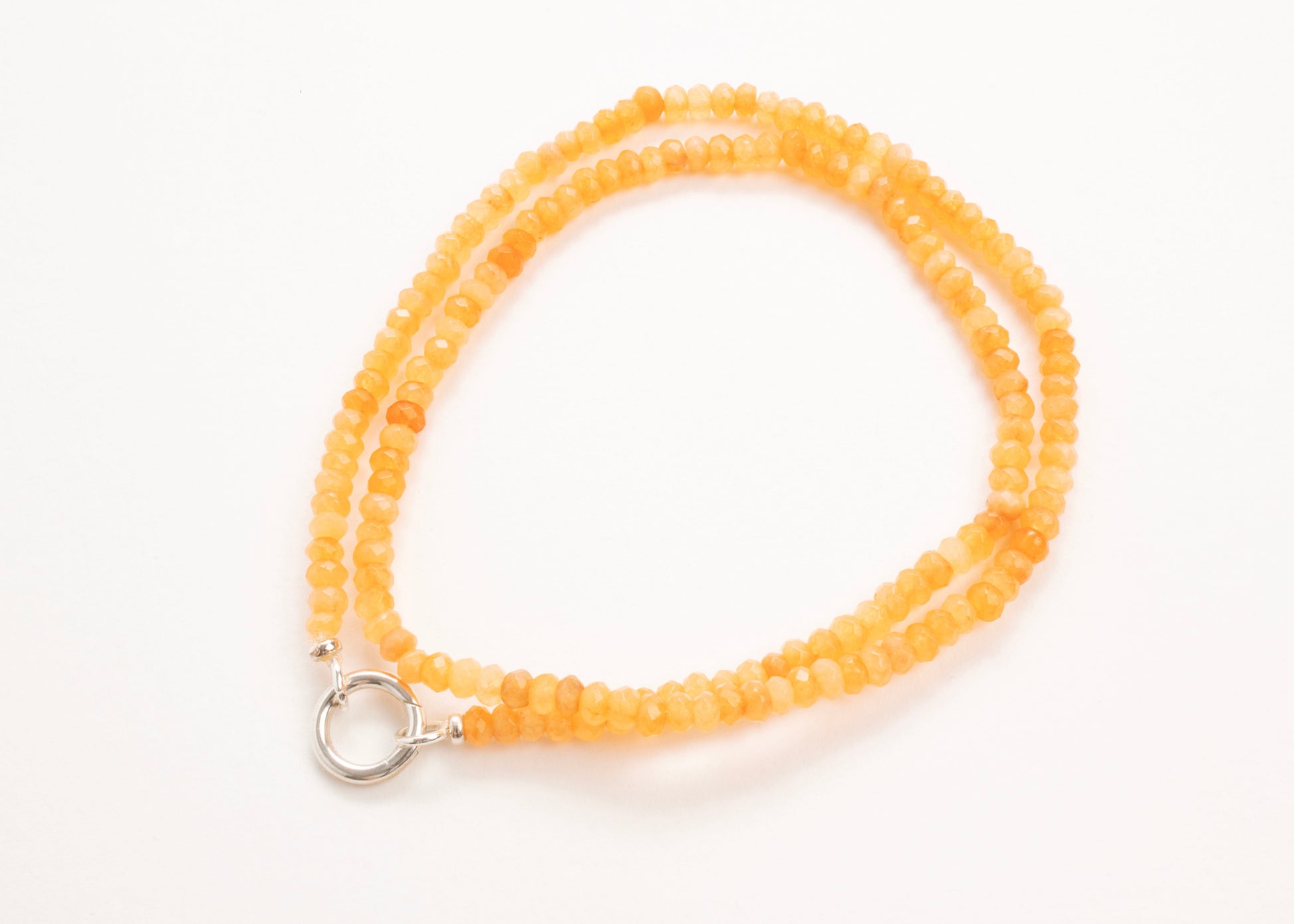 Plan view of a closed orange _small_quartzite_bead strand_wrapped_in_two_loops_on a white background