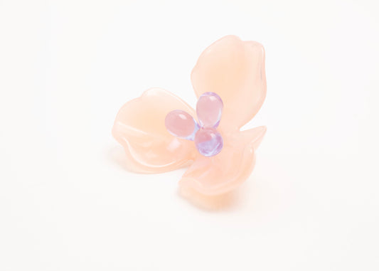 Front side close up of a peach resin_flower charm with lavender glass beads detail_and a Sterling Silver looped ending on a white background.