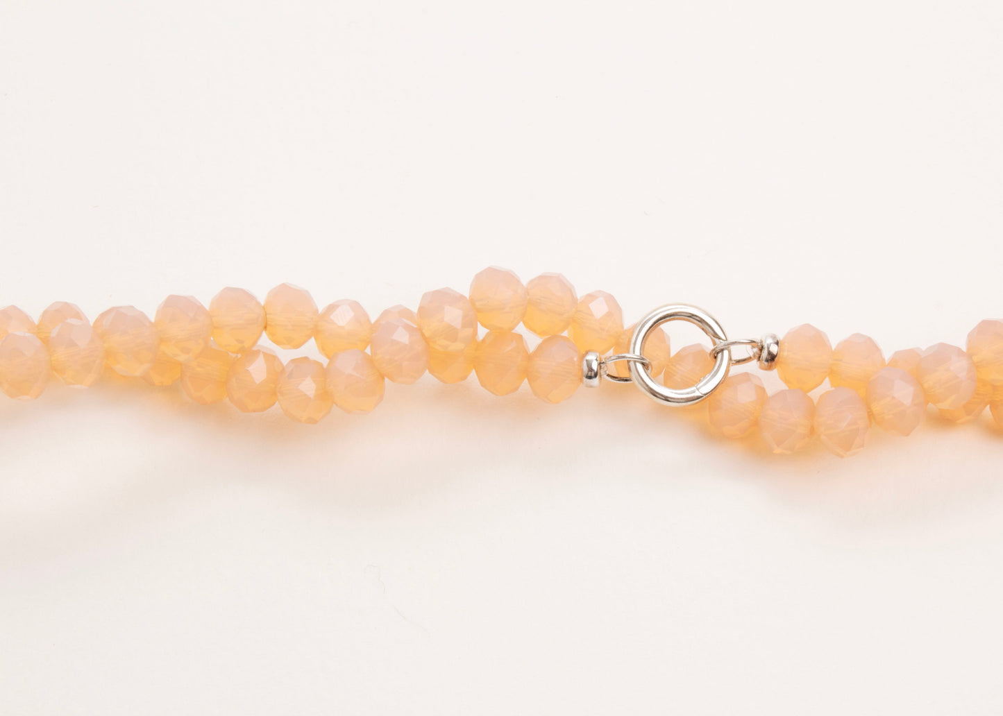 Plan_view of a peach_glass_bead_strand_wrapped_in_two_loops_on a white background.