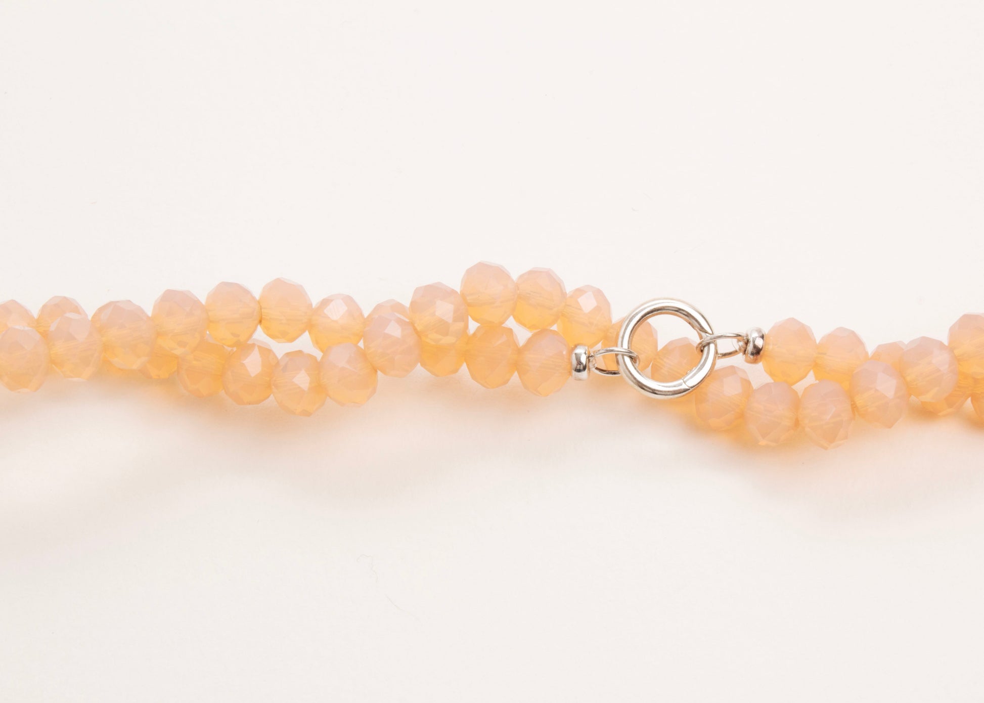 Plan_view of a peach_glass_bead_strand_wrapped_in_two_loops_on a white background.