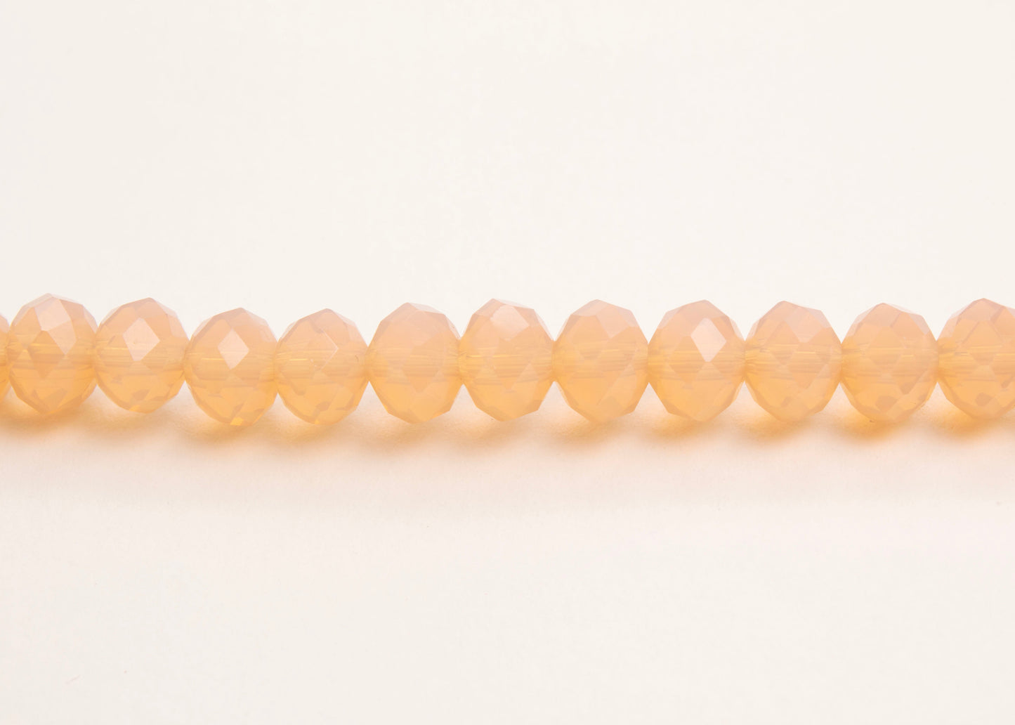 Front horizontal view of a peach_glass_beads_strand_on a white background