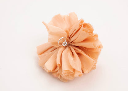 Back view of a peach silk flower charm with sterling silver loop ending on a white background.
