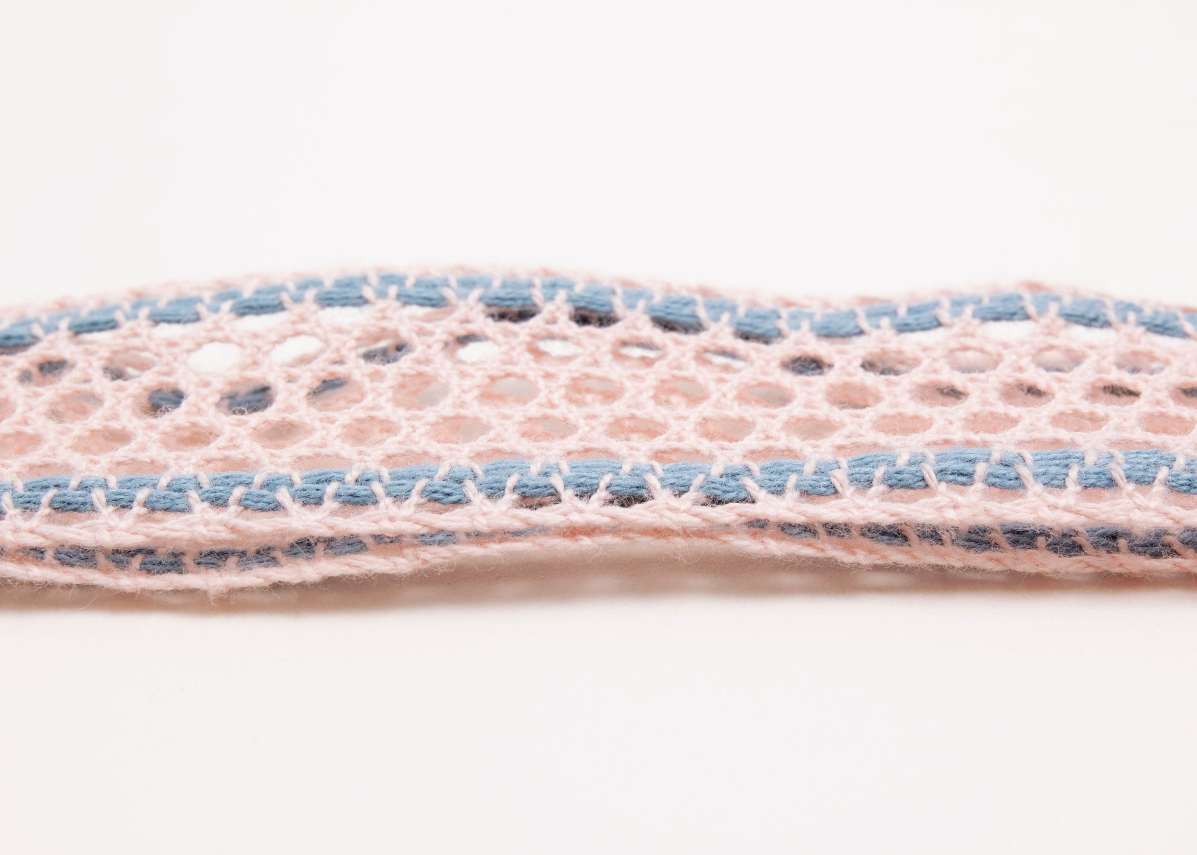 Close up detail of fabric of a cotton fishnet ribbon in pink and light blue with Sterling Silver looped endings on a white background