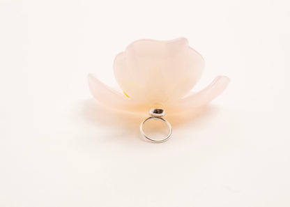 Full back close up of a peach resin_flower charm with yellow glass bead detail_and a Sterling Silver looped ending on a white background