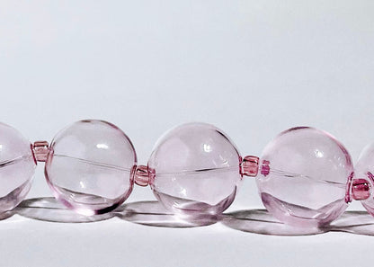 Front view close up of a pink chunky glass bead drop on a light grey background