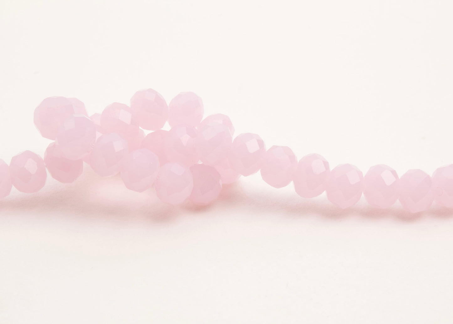 Front_view of a pink_rondelles_glass_bead_strand_knotted_on a white background.