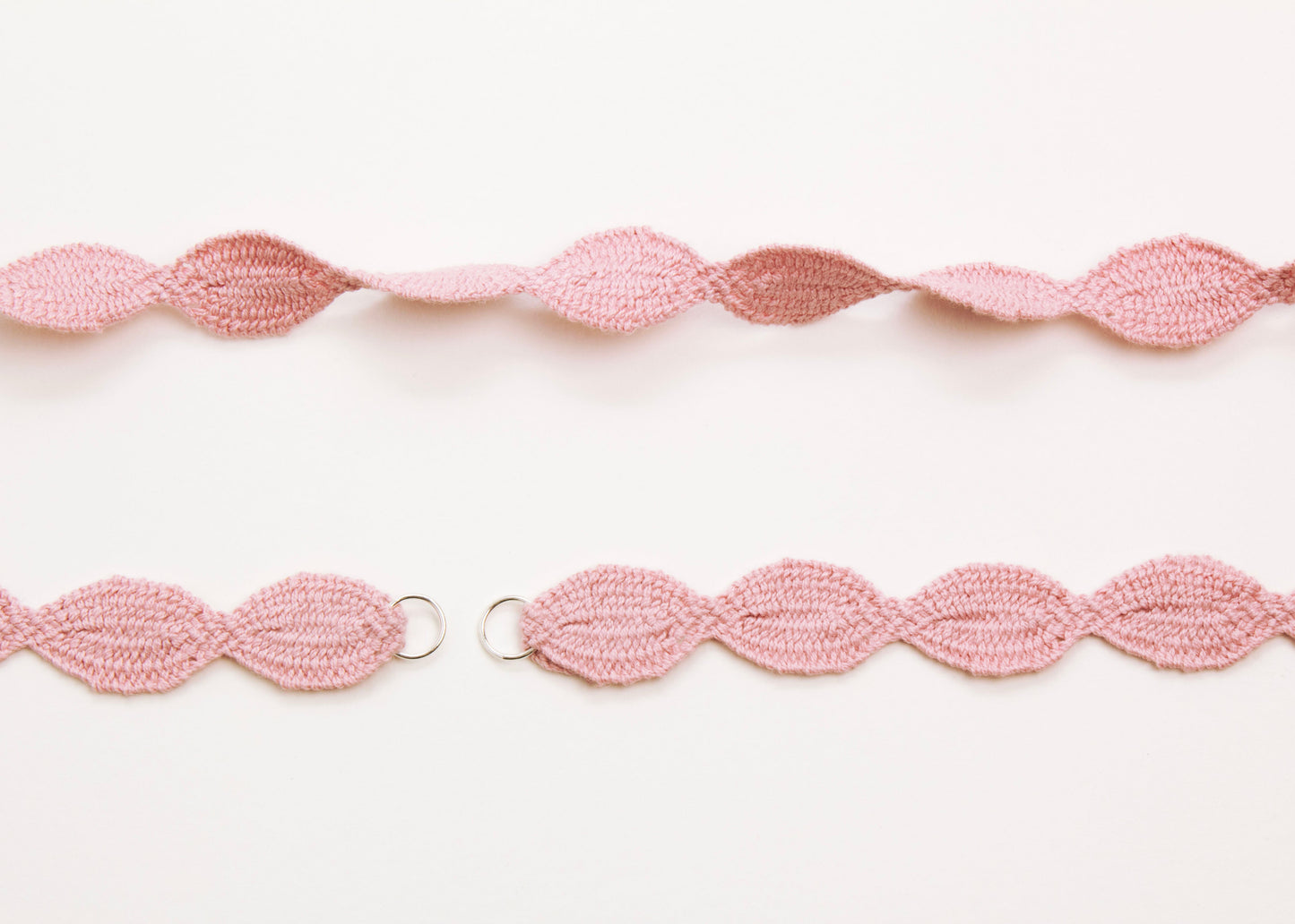 Plan view of a pink woven cotton ovals necklace with Sterling Silver looped ends a white background