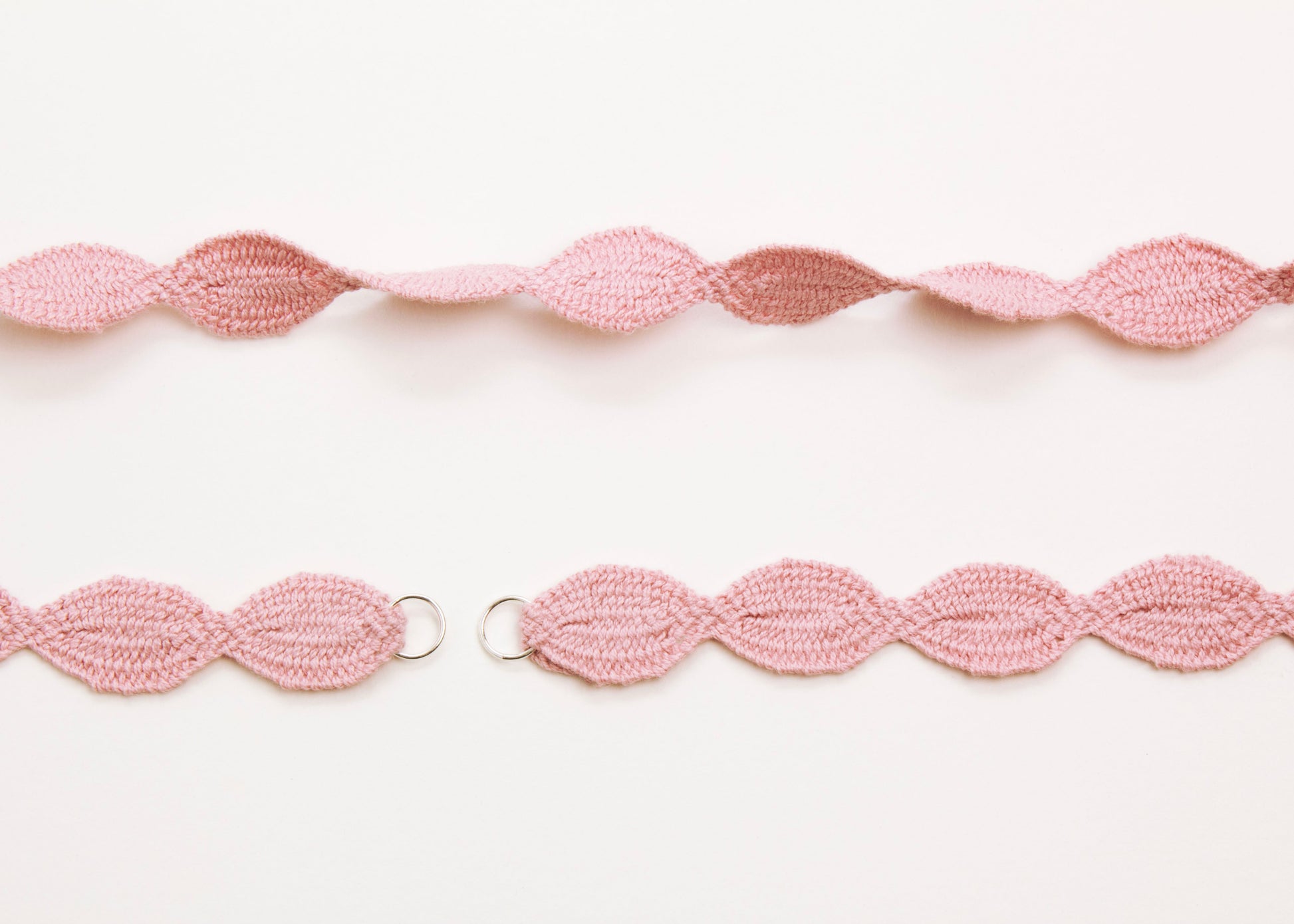 Plan view of a pink woven cotton ovals necklace with Sterling Silver looped ends a white background