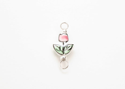 Close up of a hand painted porcelain tulip charm  on a white background