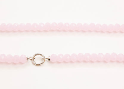 Close-up of a pink glass beaded necklace with a sterling silver clasp on a white background