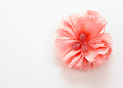 Front view of a pink silk flower charm with glass detail in center on a white background.