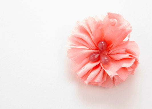 Front view of a pink silk flower charm with glass detail in center on a white background.