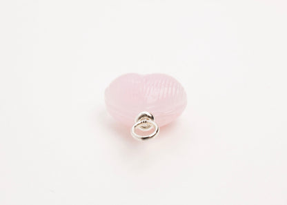Ending close up of pink glass heart charm placed on white background.