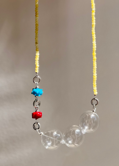 Quartize bead strand with chunky clear bead drop and two urchin charms against a neutral background