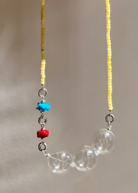 Quartize bead strand with chunky clear bead drop and two urchin charms against a neutral background
