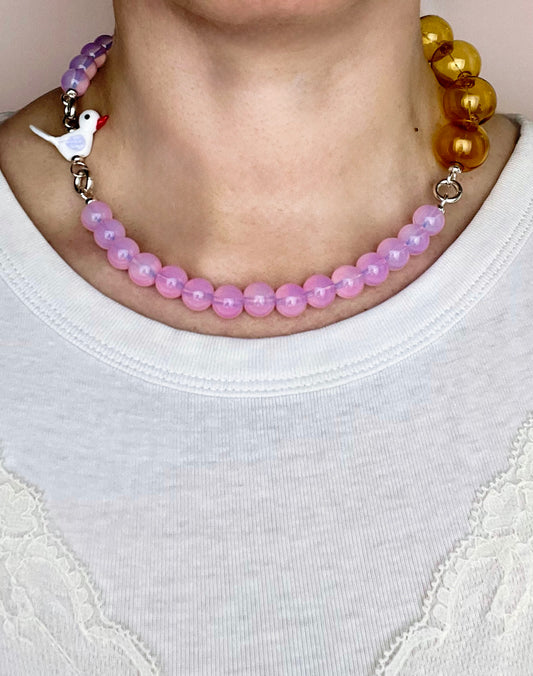 Front view of an deep pink opalite necklace on a round neck line with bird charm and mellow yellow chunky glass bead chainlet with Sterling Silver endings