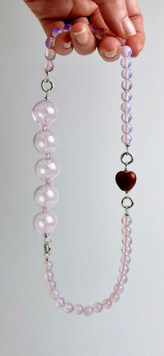 Front view of a ready to wear necklace made with pink Opalite chainlets, pink chunky glass bead drop and a red heart porcelain charm with Sterling Silver endings against a light grey back drop