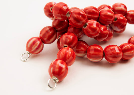 Close up of Sterling Silver looped endings detail of a red porcelain bead necklace on a white background