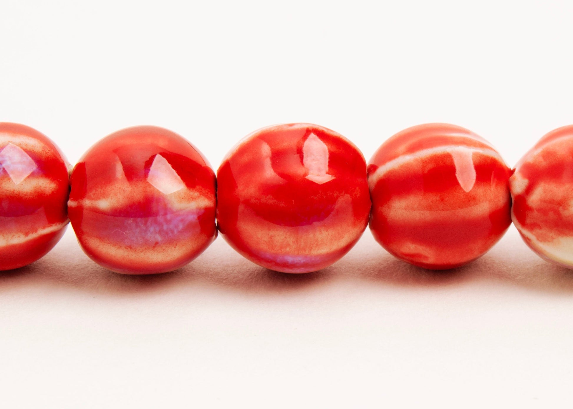 Front view of a red porcelain bead necklace with bumpy stripes on a white background