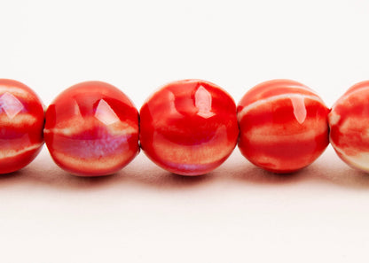 Front view of a red porcelain bead necklace with bumpy stripes on a white background