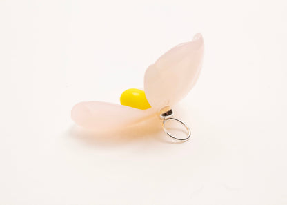 Back left side close up of a pink resin_flower charm with yellow glass beads detail_and a Sterling Silver looped ending on a white background.