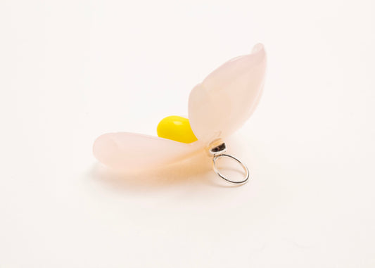 Back left side close up of a pink resin_flower charm with yellow glass beads detail_and a Sterling Silver looped ending on a white background.