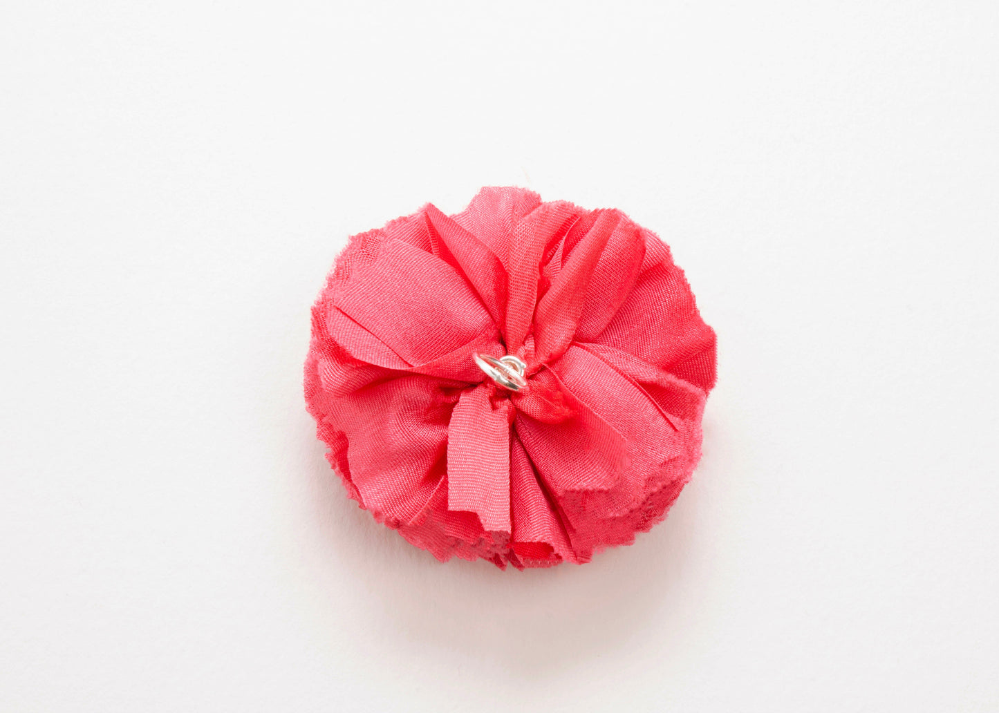 Back view of a rose red silk flower charm with sterling silver loop end on a white background.