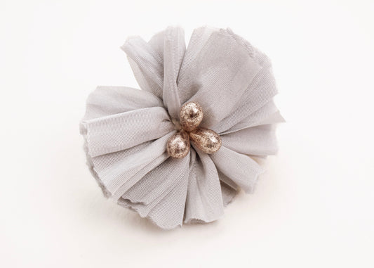 Front view of a silver silk flower charm with glass detail in center on a white background.