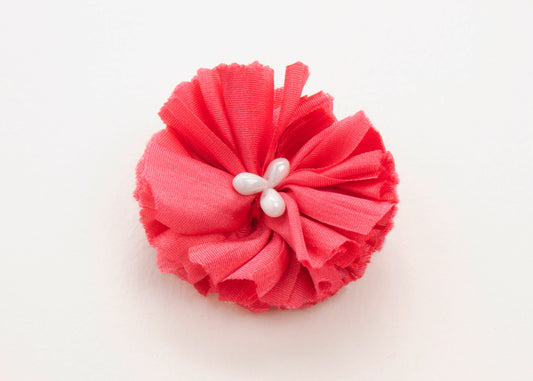 Coral red flower connector and charm with pearled white glass bead trio in the centre on a white background.