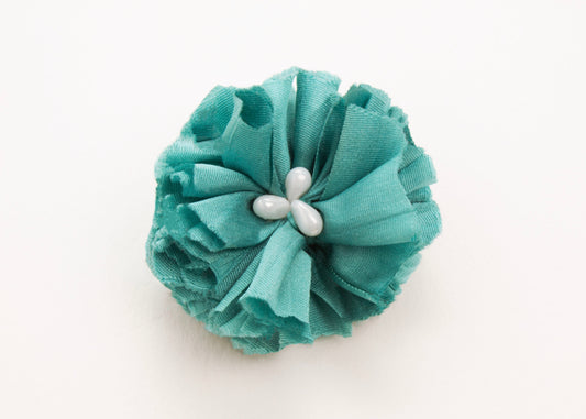Teal flower connector and charm with pearled white glass beads in the centre on a white background.