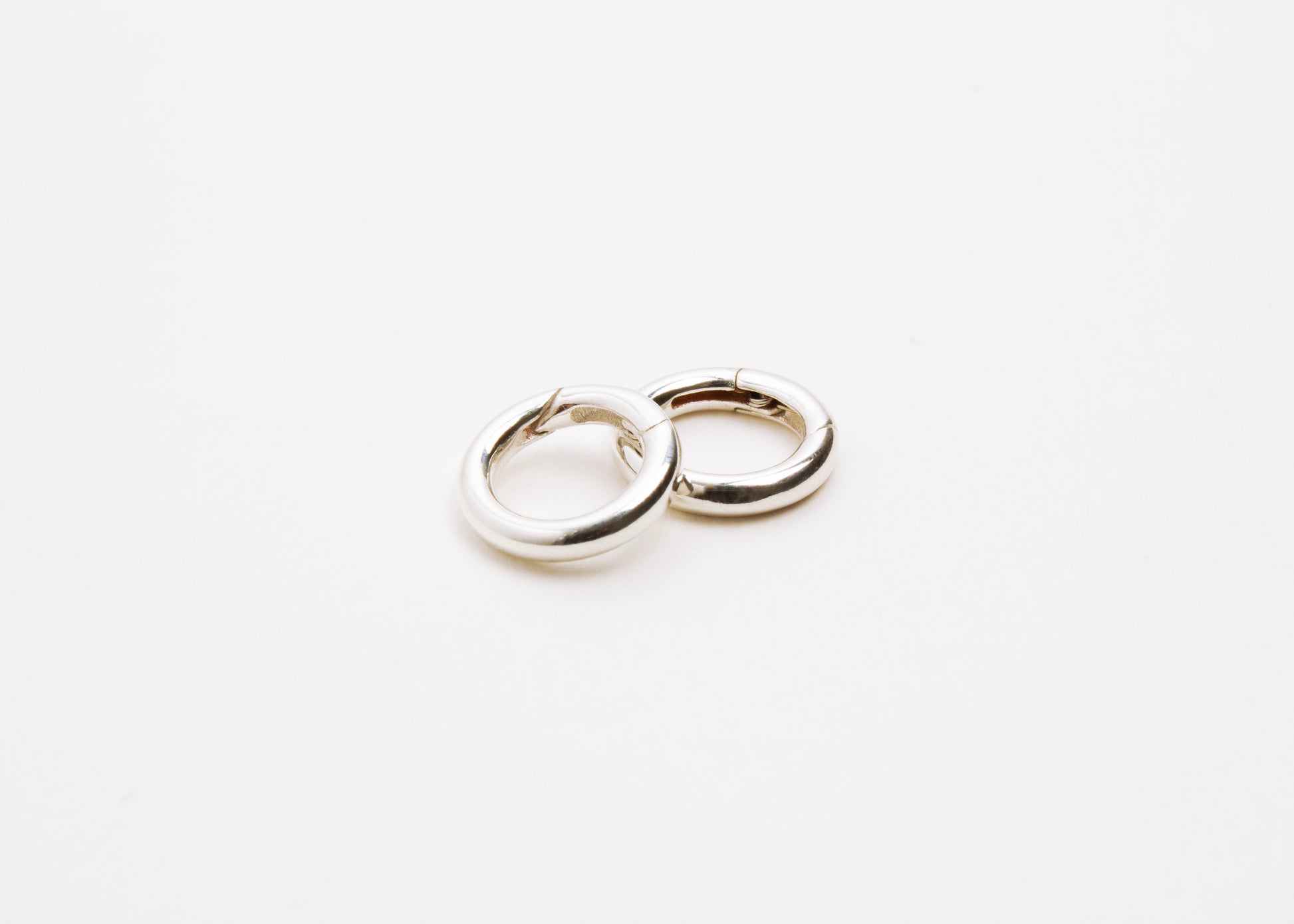 Close up of two Sterling Silver Spring Gate locks on a light grey background