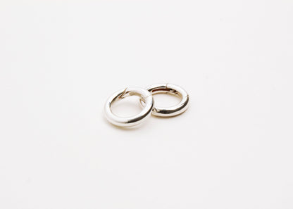Close up of two Sterling Silver Spring Gate locks on a light grey background