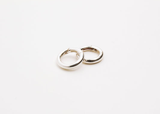 Close up of two Sterling Silver Spring Gate locks on a light grey background
