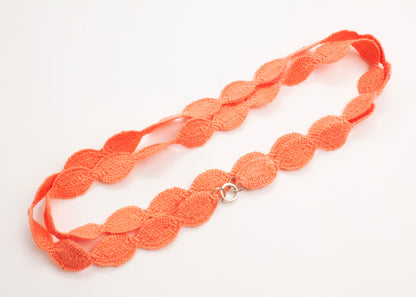 Plan view of a orange red cotton woven ovals necklace with Sterling Silver looped ends on a white background