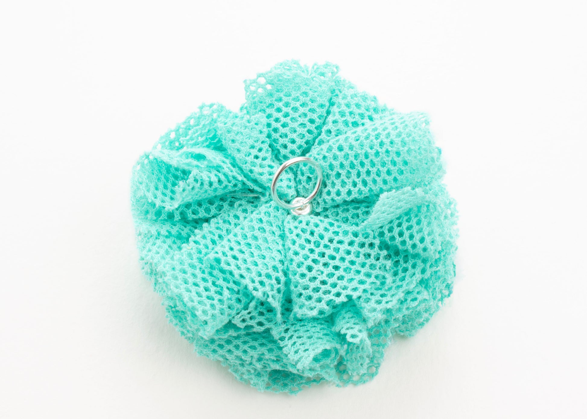 Back view of a turquoise point de tulle flower charm with Sterling Silver ending on a white background