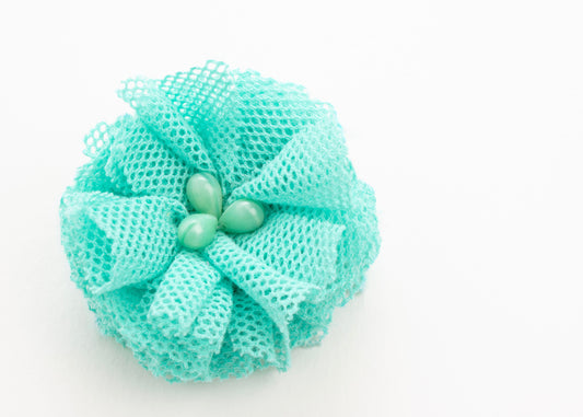 Front view of a turquoise point de tulle flower charm with glass bead detail on a white background