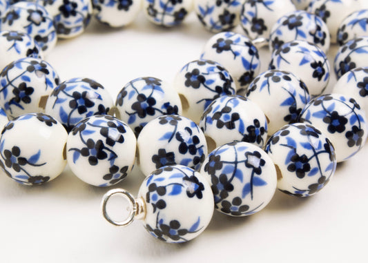 Close up of Sterling Silver looped ending of a white porcelain with blue hand painted flowers on a white background