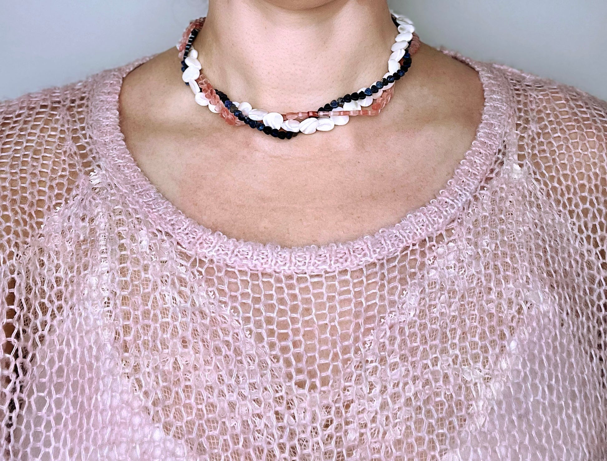 Front view of a woman wearing layered necklaces made out of Mop, Lapis lazuli and cherry quartz gemstone heart beads