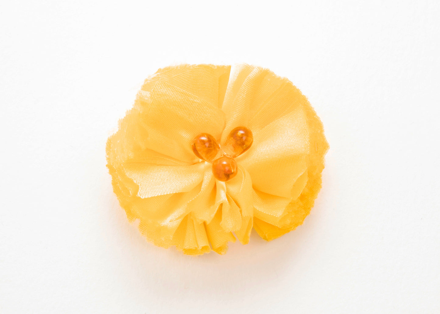 Front view of a yellow silk flower charm with glass detail in center on a white background.