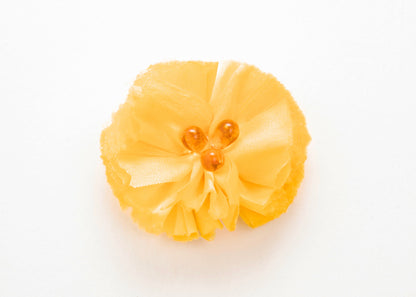 Front view of a yellow silk flower charm with glass detail in center on a white background.
