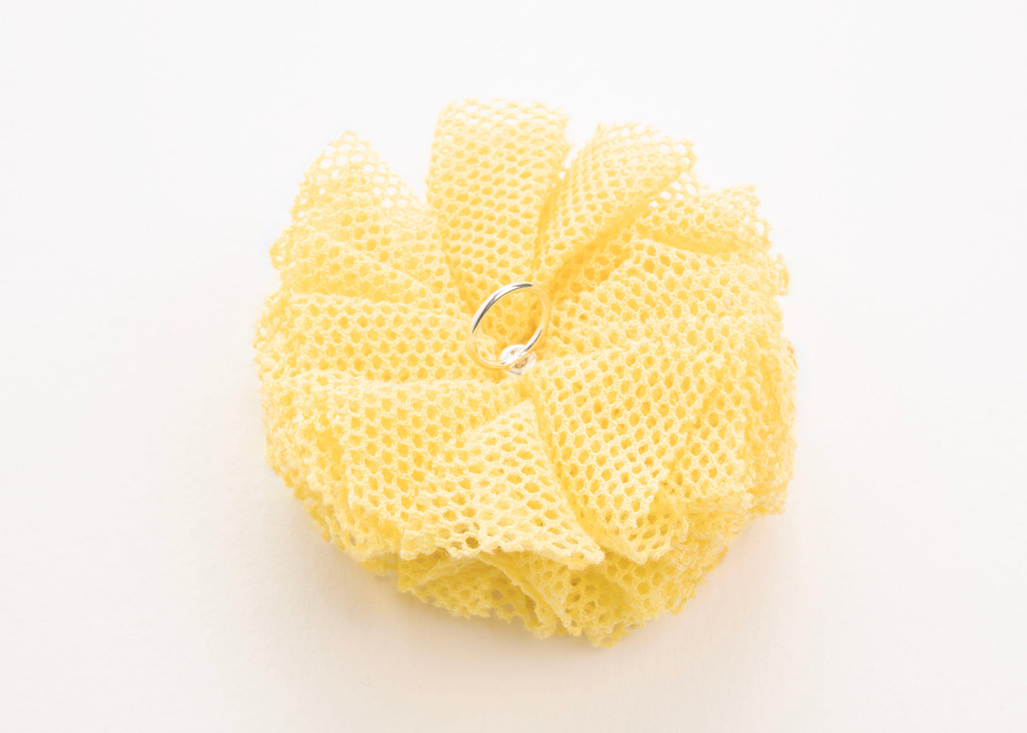 Back view of a yellow point de tulle flower charm with Sterling Silver ending on a white background
