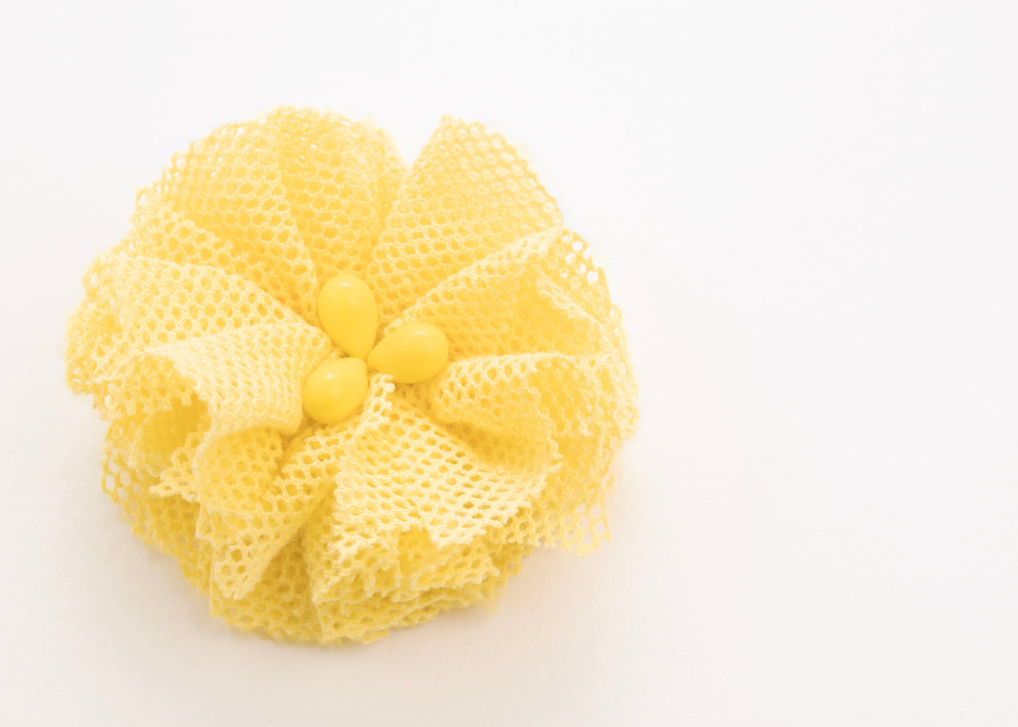 Front view of a yellow  point de tulle flower charm with glass beads detail on a white background