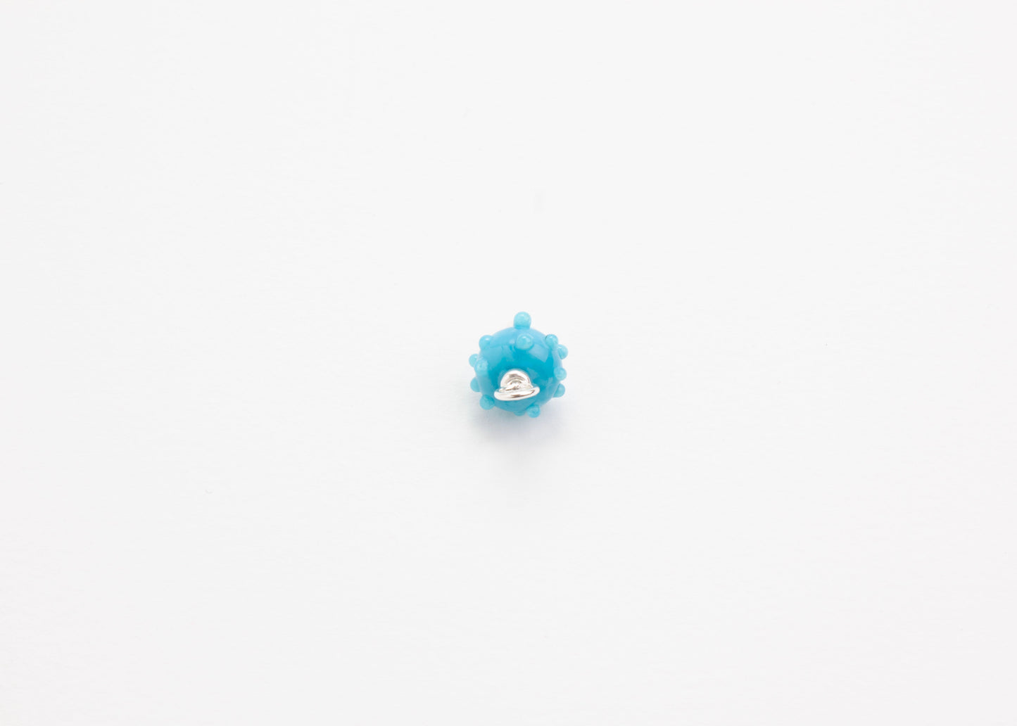 Front view of an urchin lampwork glass blue charm with Sterling Silver ends in a white background