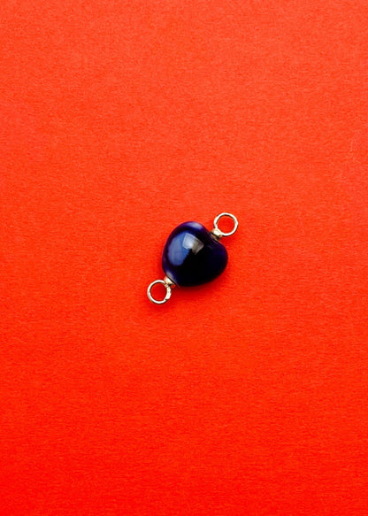 close up of a chunky blue porcelain heart charm with Sterling Silver endings on a red background